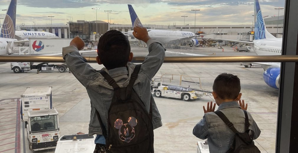 Two children watching airplanes at airport